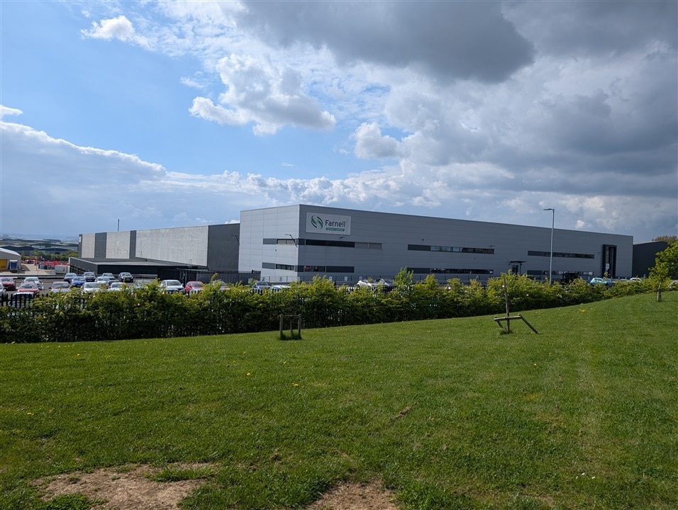 A grassy area with a large warehouse building in the background