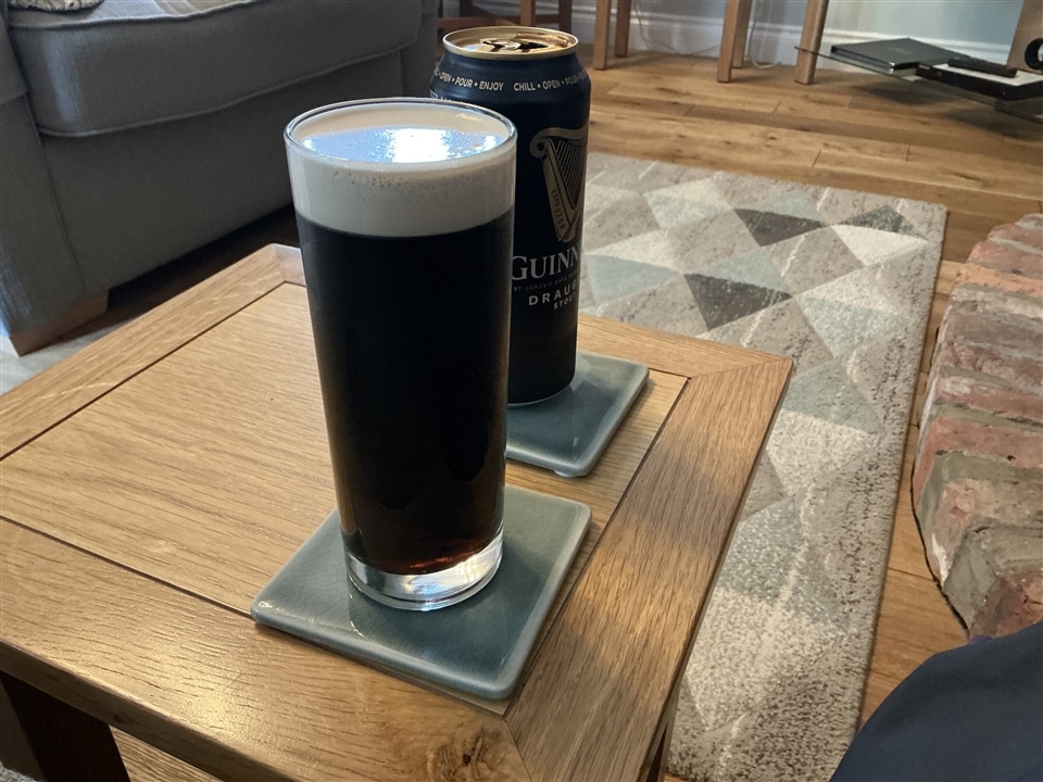 Small table with a glass filled with Guinness and the Guinness can behind it